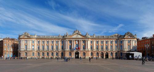 a large building with people walking in front of it at Hôtel & Résidence Octel in Portet-sur-Garonne
