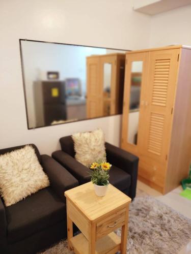 a living room with a black couch and a table at Green 2 Residences in Dasmariñas