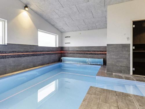 a swimming pool with blue water in a building at 5 star holiday home in Væggerløse in Bøtø By