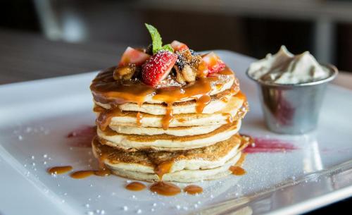 a stack of pancakes with strawberries and syrup on a plate at Hotel Saffron kiran By Aamod Suites in Dalhousie