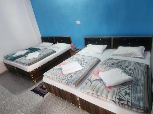 two twin beds in a room with blue walls at Hotel Namami Gange & Restaurant in Kedārnāth