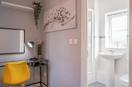a bathroom with a yellow chair and a sink at The Rainbow Retreat by Sheppey Stays in Iwade
