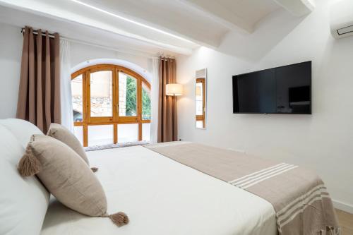 a bedroom with a large bed with a flat screen tv at Hauzify I Apartaments La Plaça in Montblanc