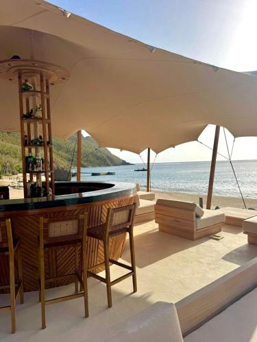 a bar with chairs and an umbrella on the beach at Tenuta Chatham Bay in Union Island