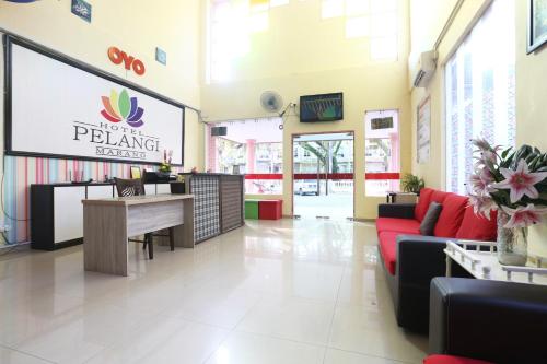 a lobby of a pharmacy with a couch and a table at Hotel O Pelangi Marang in Marang