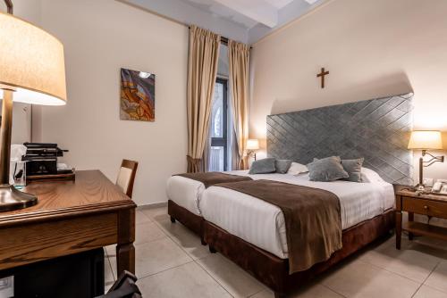 a bedroom with a large bed and a desk and a bed sidx sidx sidx sidx at Notre Dame of Jerusalem Center in Jerusalem