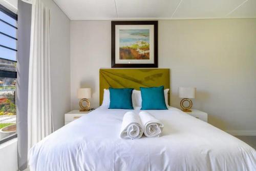 Un dormitorio con una gran cama blanca con almohadas azules. en #AlimamaSpaces The Manson Munyaka Villa, en Vosburg