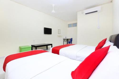 two beds in a room with red pillows at Hotel O Pelangi Marang in Marang