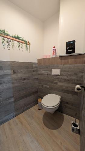a bathroom with a toilet and a wooden wall at Les roches voisines little rock in Solutré-Pouilly
