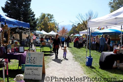 a woman and a child walking through an outdoor market at She Shes Downtown Salidas Sunny Overlook in Salida