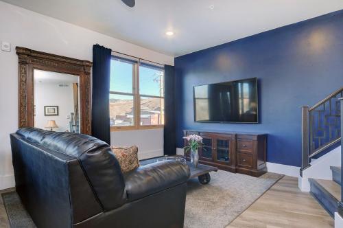 a living room with a leather couch and a blue wall at She Shes Downtown Salidas Sunny Overlook in Salida