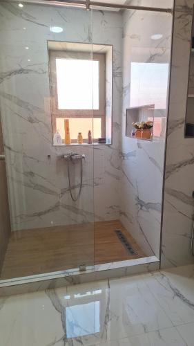 a bathroom with a glass shower with a window at Suites au sein d'une Villa au centre ville de Rabat in Rabat