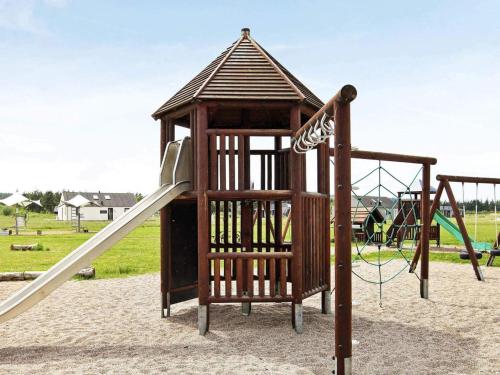 a wooden playground with a slide in a park at Luxury Retreat Tranum Strand - By Traum Ferienwohnungen in Brovst