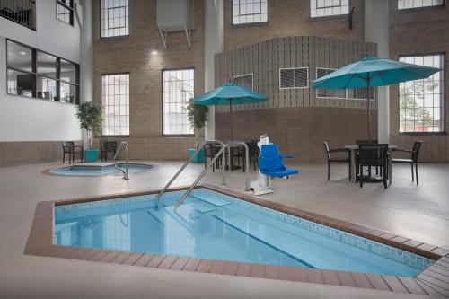 a pool with tables and umbrellas in a building at The Suites Hotel at Waterfront Plaza in Duluth
