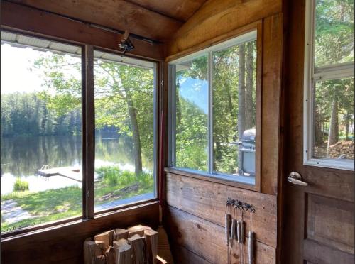 a room with three windows and a view of a lake at Algonquin Waterfront and Winter Paradise With Sunsets in Algonquin Highlands