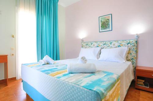 a bedroom with a large bed with blue curtains at Zouli Sophia in Kalami