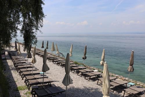 a row of chairs with umbrellas and the ocean at Monika Holiday 315 Magic Lake in Garda