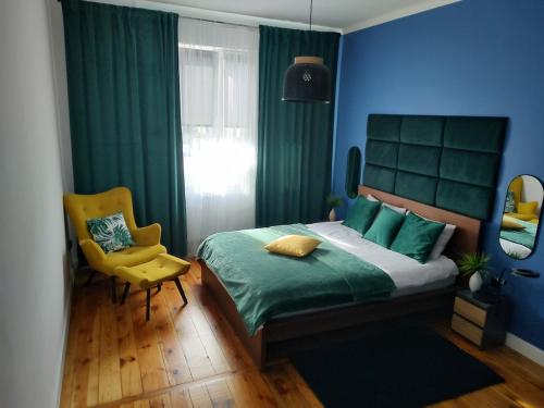 a blue bedroom with a bed and a yellow chair at Cozy Calming Apartment in Poznań