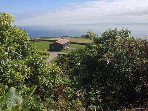 a barn on a hill with the ocean in the background at Pico da Vigia in Santa Bárbara