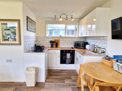 a kitchen with white appliances and a wooden table at 197 Broadside Holiday Chalet near Broads & Beaches in Stalham