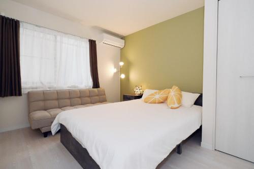 a bedroom with a large white bed and a couch at Taito City Negishi 2Ldk-TT0323 in Tokyo