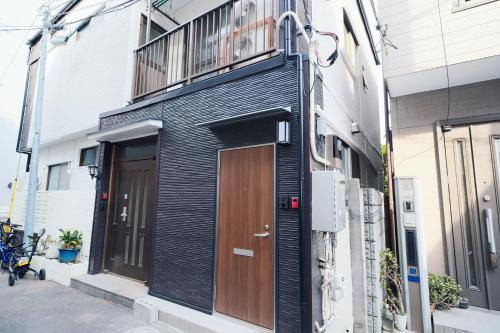 a black building with a wooden door and a balcony at Taito City Negishi 2Ldk-TT0323 in Tokyo