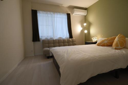 a bedroom with a bed and a couch and a window at Taito City Negishi 2Ldk-TT0323 in Tokyo