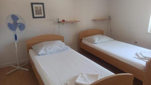 two twin beds in a room with a fan at Apartmani Zulin in Seget Vranjica