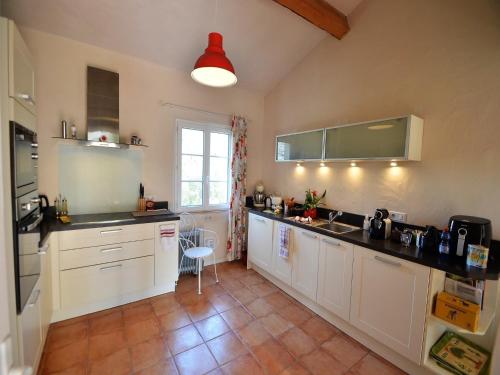 a large kitchen with white cabinets and a red light at Holiday Home Montaigu-de-Quercy Lake in Montaigu-de-Quercy