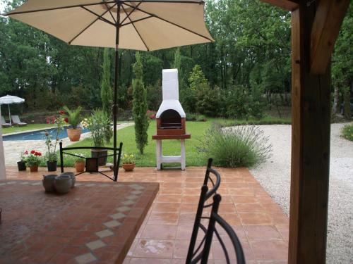 an outdoor patio with an umbrella and a grill at Holiday Home Montaigu-de-Quercy Lake in Montaigu-de-Quercy