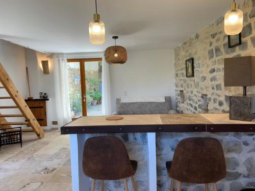 eine Küche mit einer Theke und zwei Hockern in der Unterkunft Le Petit Gîte in Vaison-la-Romaine