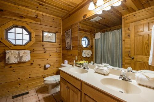 a bathroom with two sinks and a toilet in a log cabin at Absolutely Fabulous by American Patriot Getaways in Park Settlement