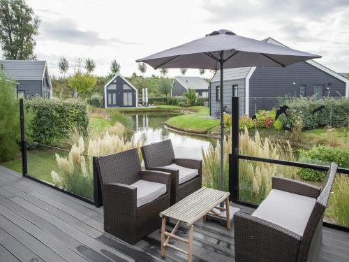 a deck with chairs and an umbrella and a table at Chalet in Kattendijke near Eastern Scheldt in Kattendijke
