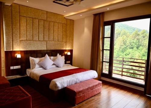 a bedroom with a large bed and a large window at Hotel Saffron kiran By Aamod Suites in Dalhousie