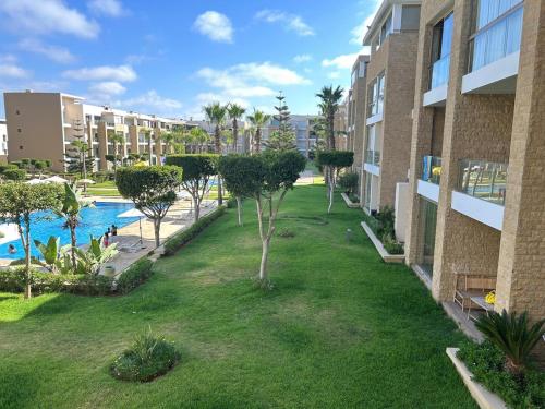 an apartment complex with a yard with a swimming pool at Cozy Beach Stay with Pool Near Rabat in Sidi Bouqnadel