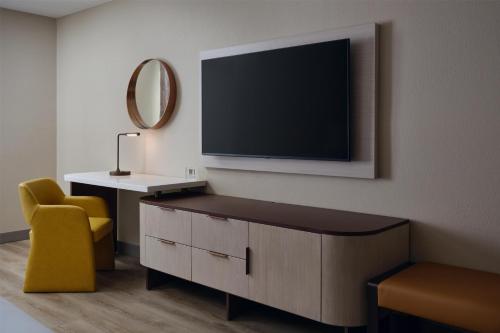 a living room with a tv and a yellow chair at DoubleTree by Hilton Brunswick in Parkwood