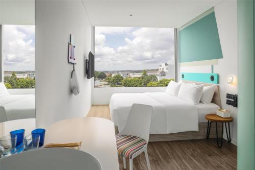 a hotel room with a white bed and a large window at Tru by Hilton Buon Ma Thuot City Centre in Buon Ma Thuot