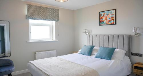a bedroom with a bed with blue pillows and a window at The Clarence Gardens Hotel, BW Signature Collection in Scarborough