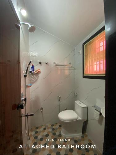 a bathroom with a white toilet and a shower at Spandana - Villa at Honnavar in Honāvar
