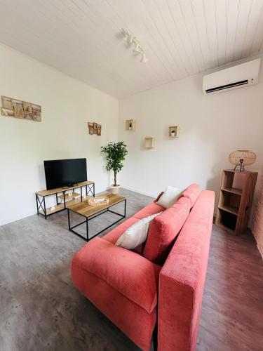 ein Wohnzimmer mit einem roten Sofa und einem Fernseher in der Unterkunft Charmant appartement rénové l Climatisé l Soual in Soual