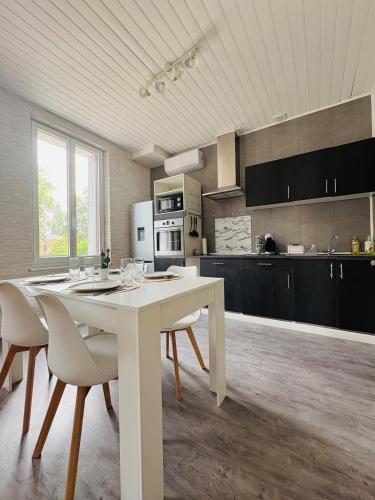eine Küche mit einem weißen Tisch und Stühlen in einem Zimmer in der Unterkunft Charmant appartement rénové l Climatisé l Soual in Soual