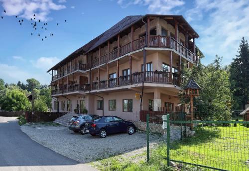 a house with two cars parked in front of it at Pensiunea Anotimpuri Bran in Bran