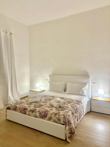 a white bedroom with a bed with two lamps at Piccola Dimora in Bitetto