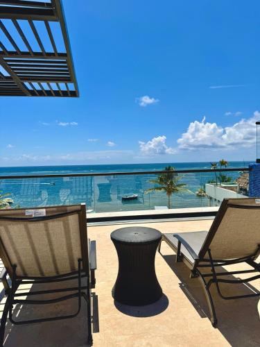 a patio with chairs and a table and a view of the ocean at Bright Ocean View Studio with Rooftop Pool Access in Puerto Morelos