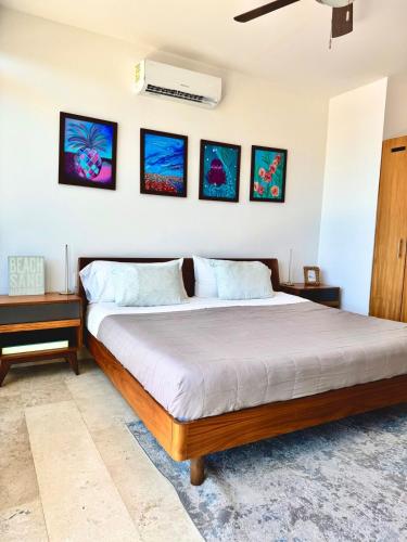 a bedroom with a bed and three pictures on the wall at Bright Ocean View Studio with Rooftop Pool Access in Puerto Morelos