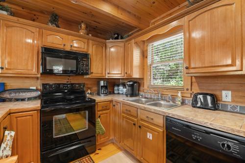 a kitchen with wooden cabinets and a black stove top oven at Beneath The Stars by American Patriot Getaways in Hatchertown