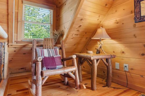 a room with a rocking chair and a table in a cabin at Beneath The Stars by American Patriot Getaways in Hatchertown