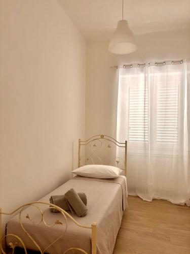 a white bedroom with a bed and a window at Piccola Dimora in Bitetto