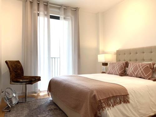 a bedroom with a bed and a chair and a window at MM1 Cosy & Central Apartment in Baixa with Castle View and Free Parking! in Lisbon