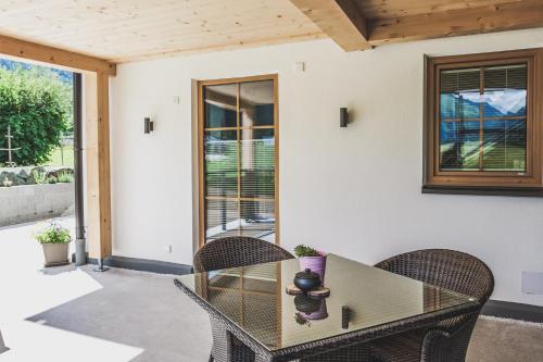 a patio with a glass table and chairs at Ur-Genuss in Heiterwang